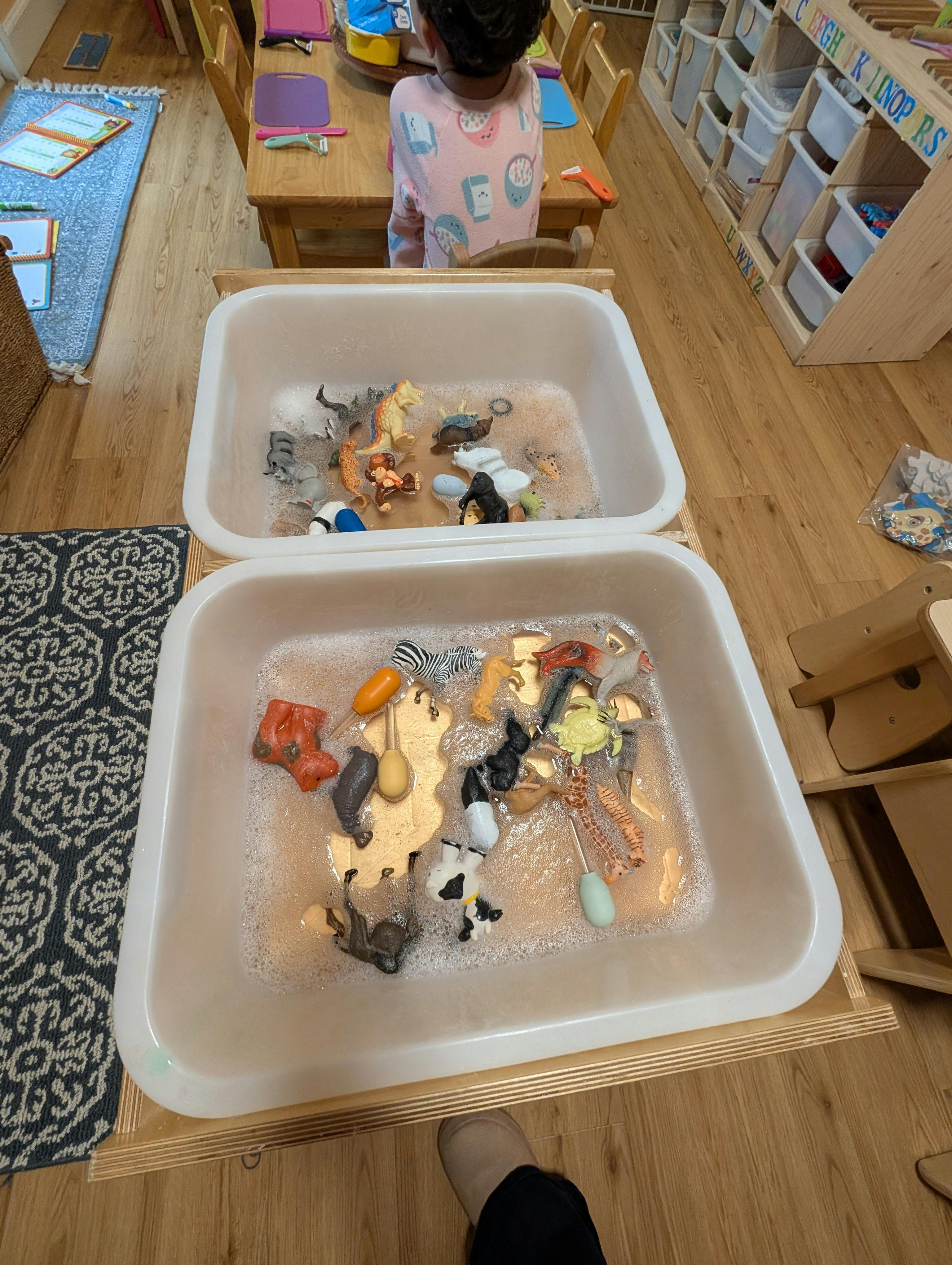 Plastic toy animals in soapy water bins