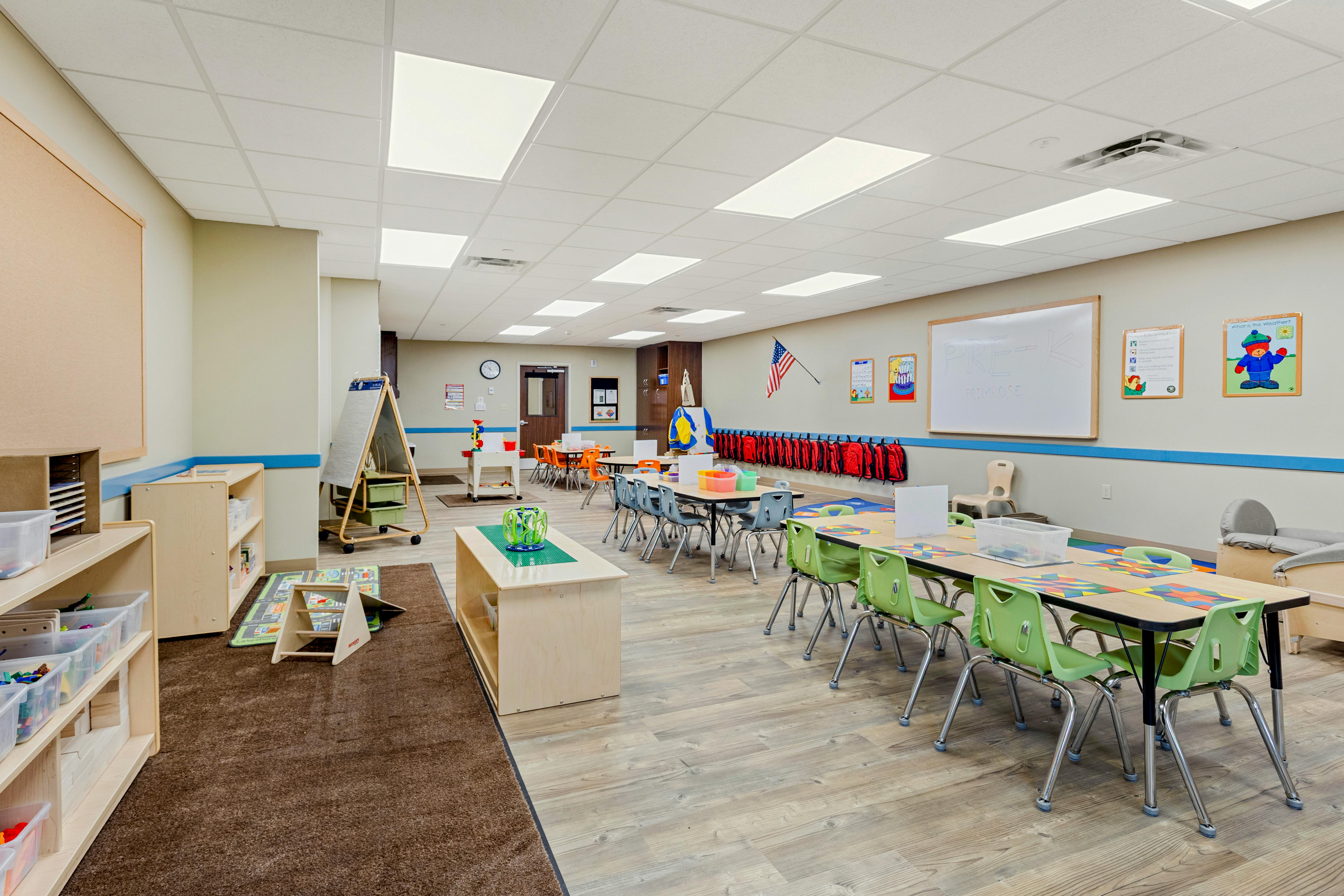 An empty early childhood classroom with multiple tables and chairs