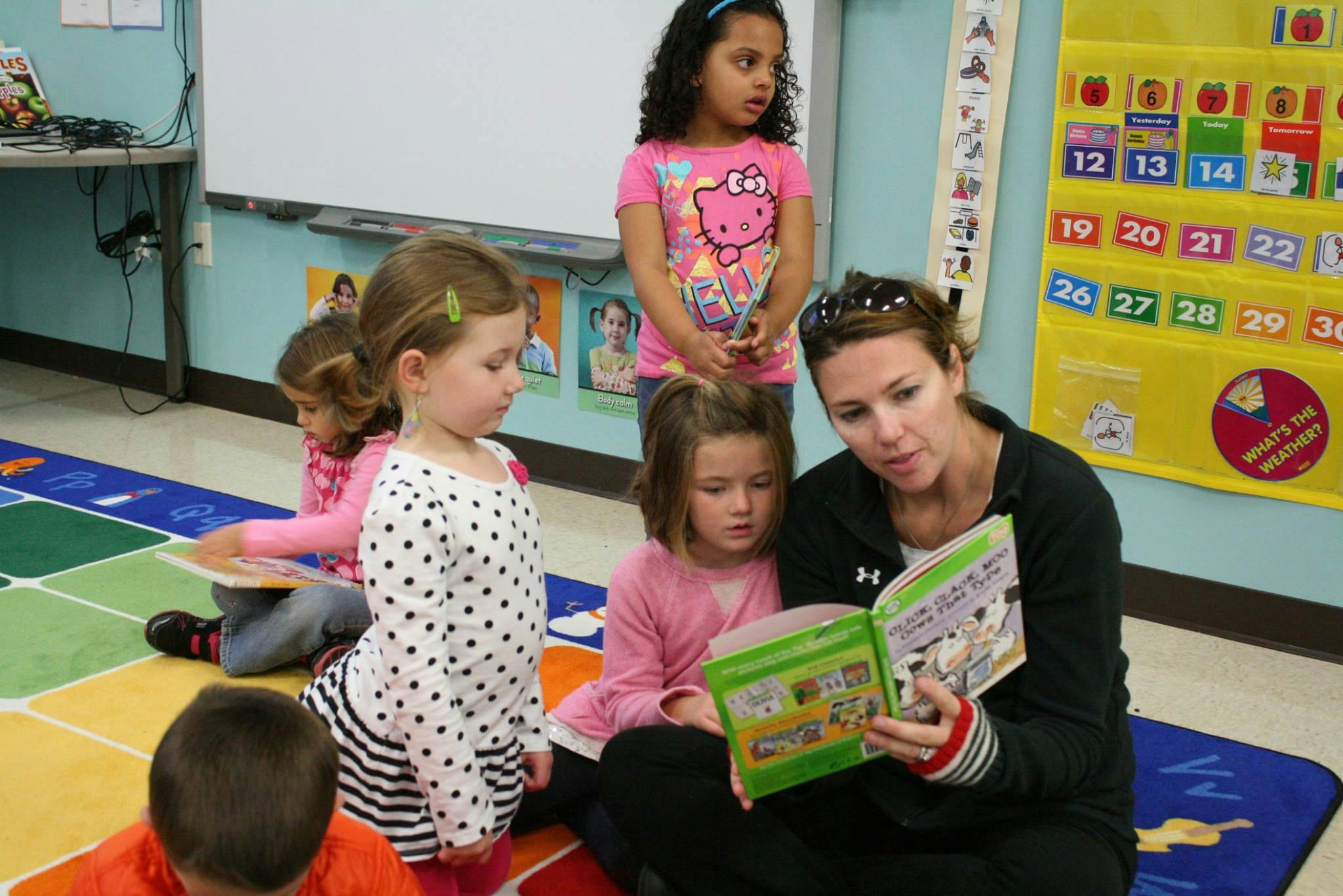 Adult reading a book to children in a classroom