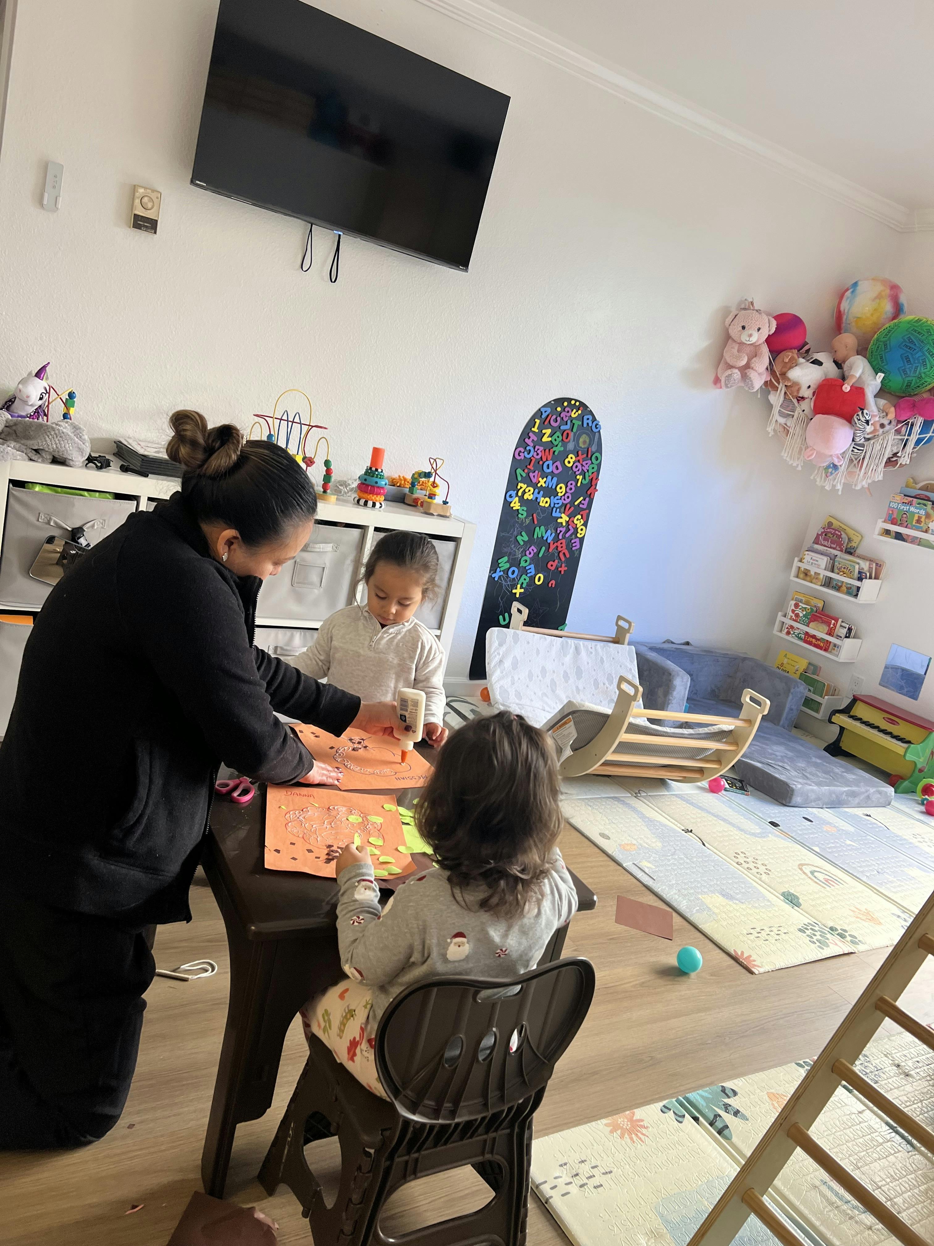 Person and two children doing crafts at a table
