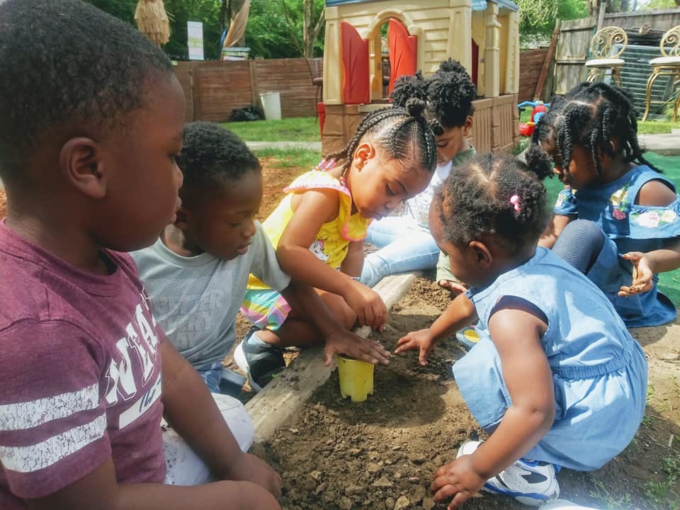 Children playing in dirt with dirt and a yellow cup