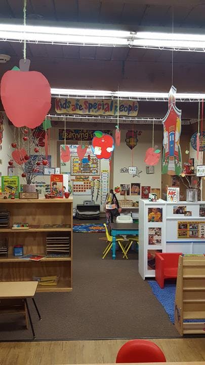 Classroom decorated with apple cutouts and a sign that reads "Kids are Special People"