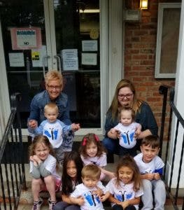 Two adults and seven children sitting on steps