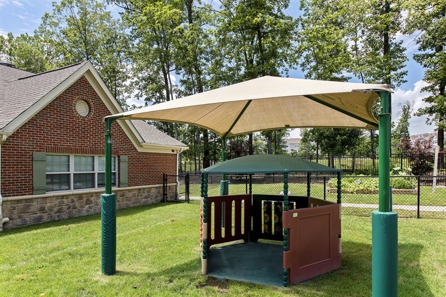 Outdoor play area with a large shade structure and a small playhouse