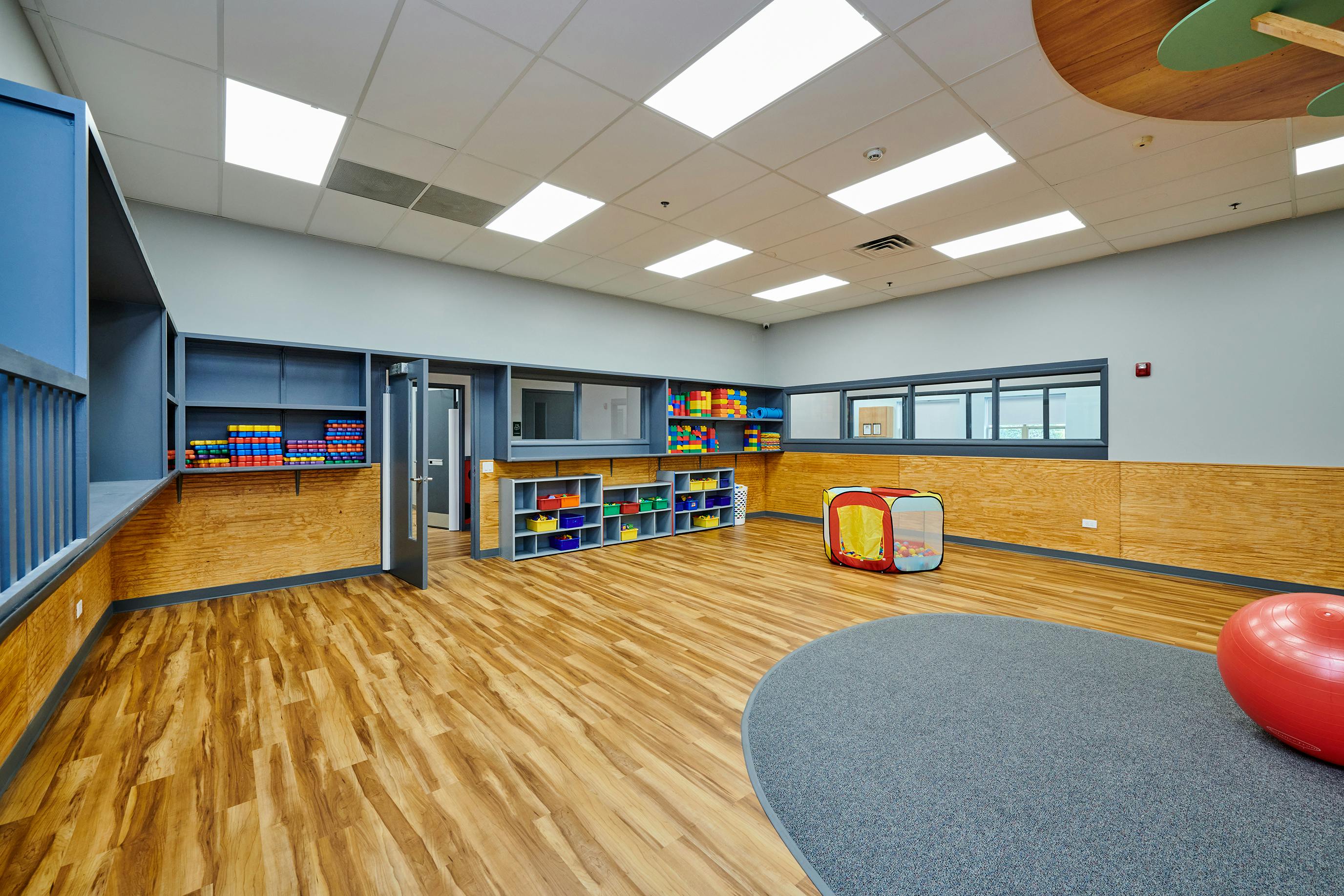Empty classroom with wooden floors and colorful storage bins