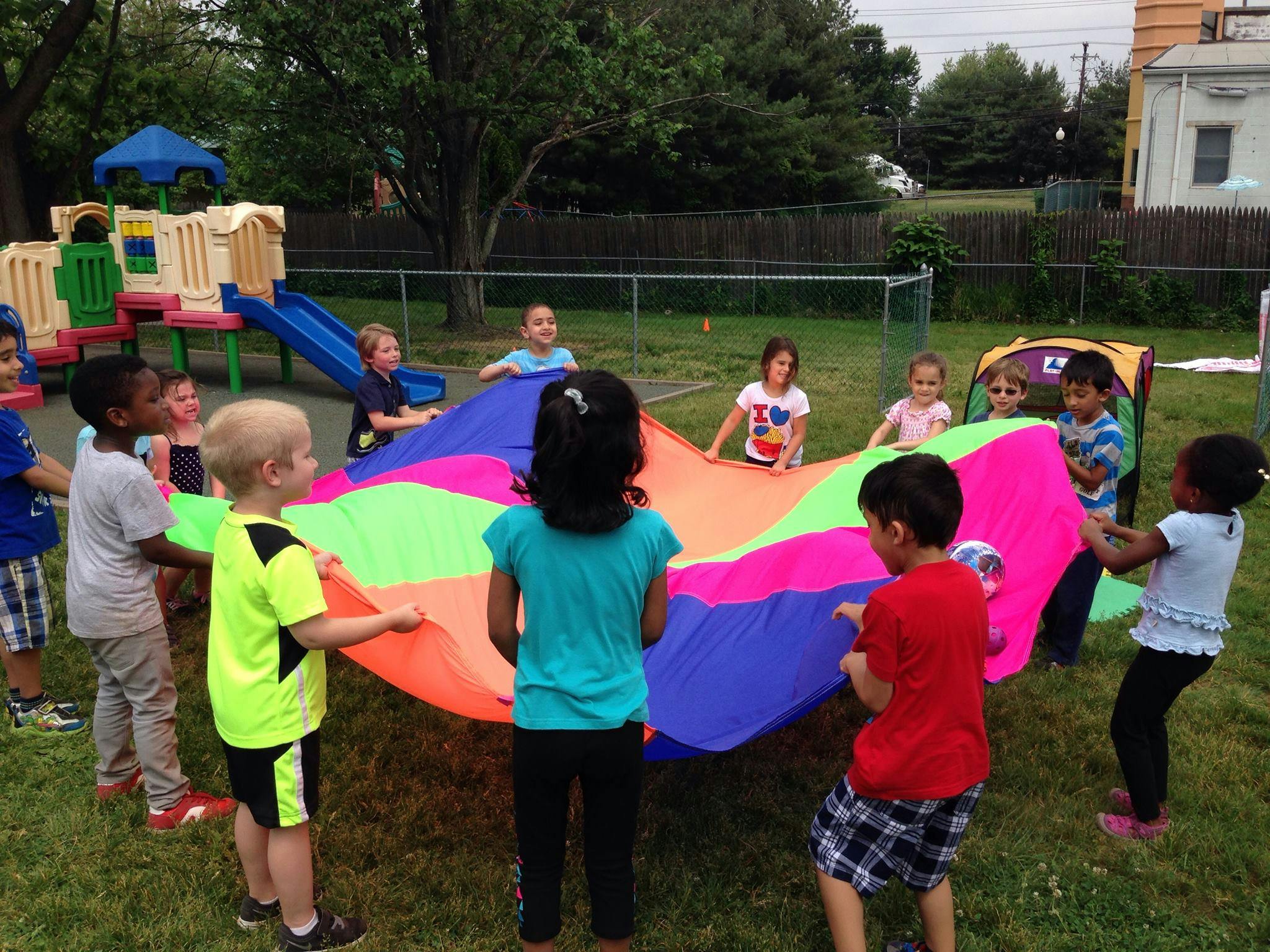Children playing with a colorful parachute outdoors