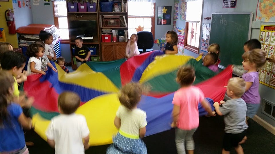 Children playing with a colorful parachute