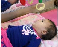 Infant lying on back looking at toys reflected toys
