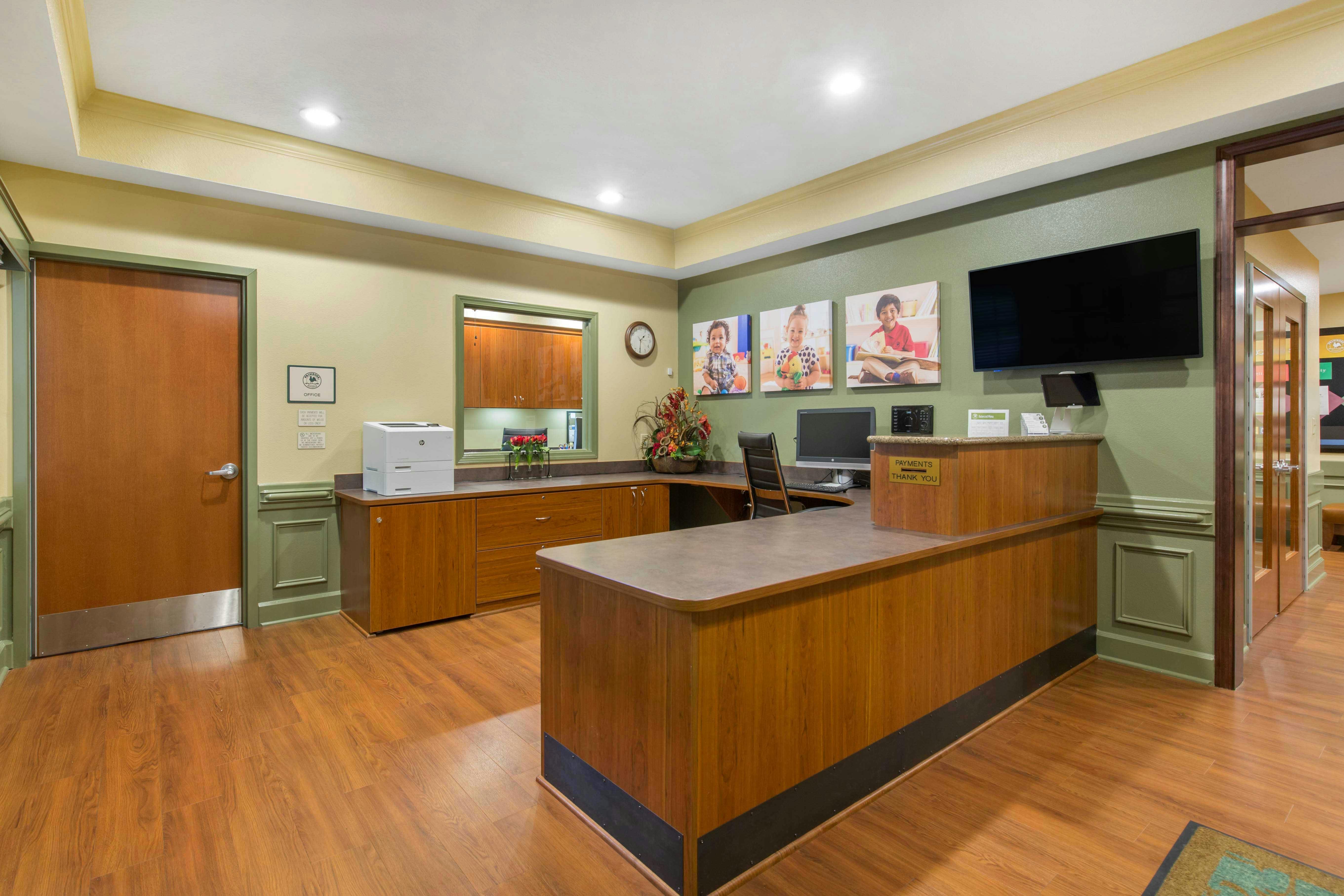 Reception desk area with computer monitor, printer, and framed pictures of children
