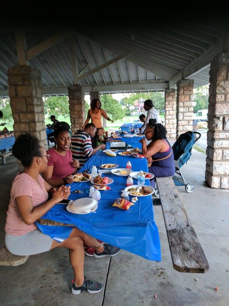 People eating at picnic tables under a pavilion