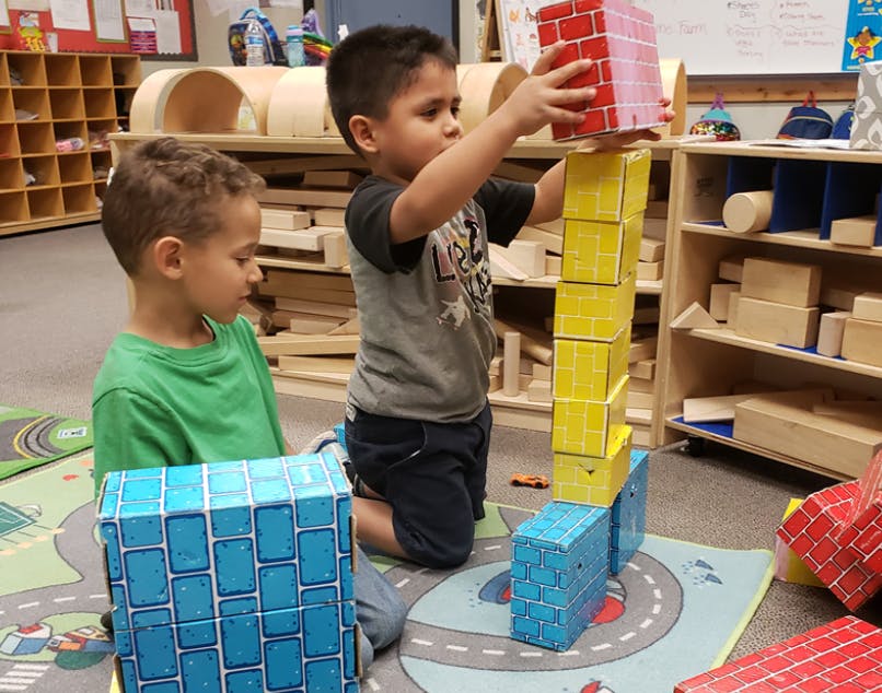 Two children playing with blocks in a classroom
