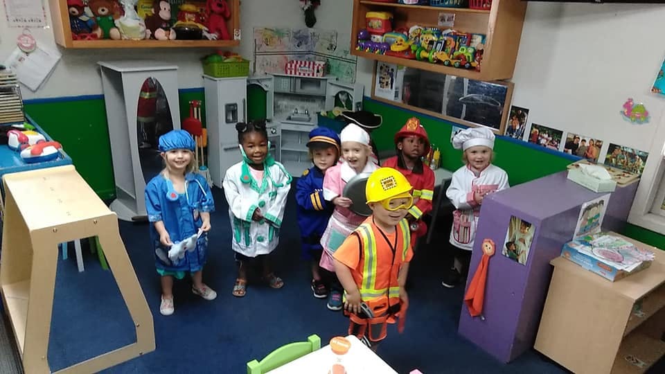 Group of children in various career costumes in a classroom