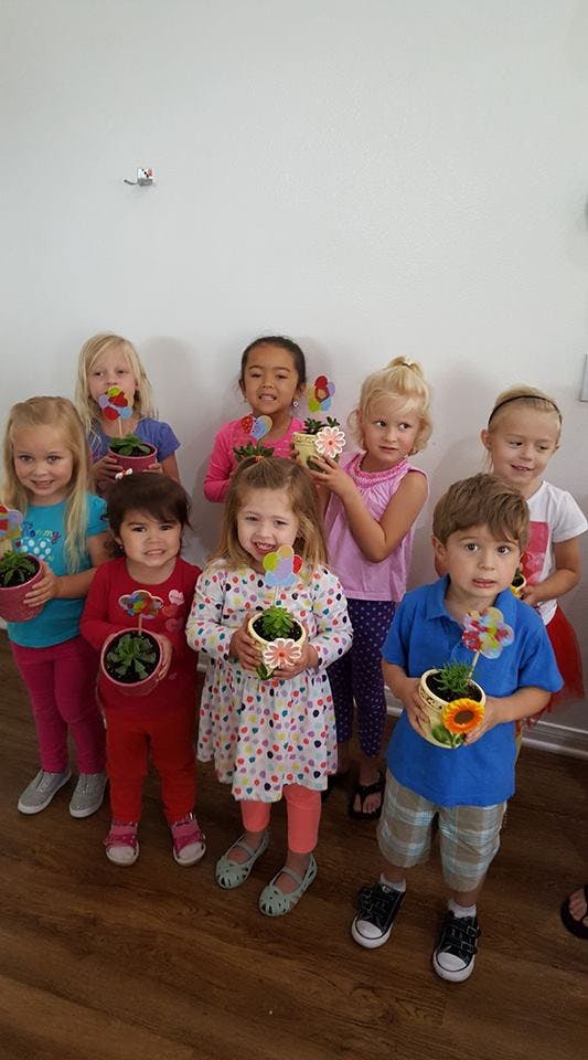 Group of children holding small potted plants