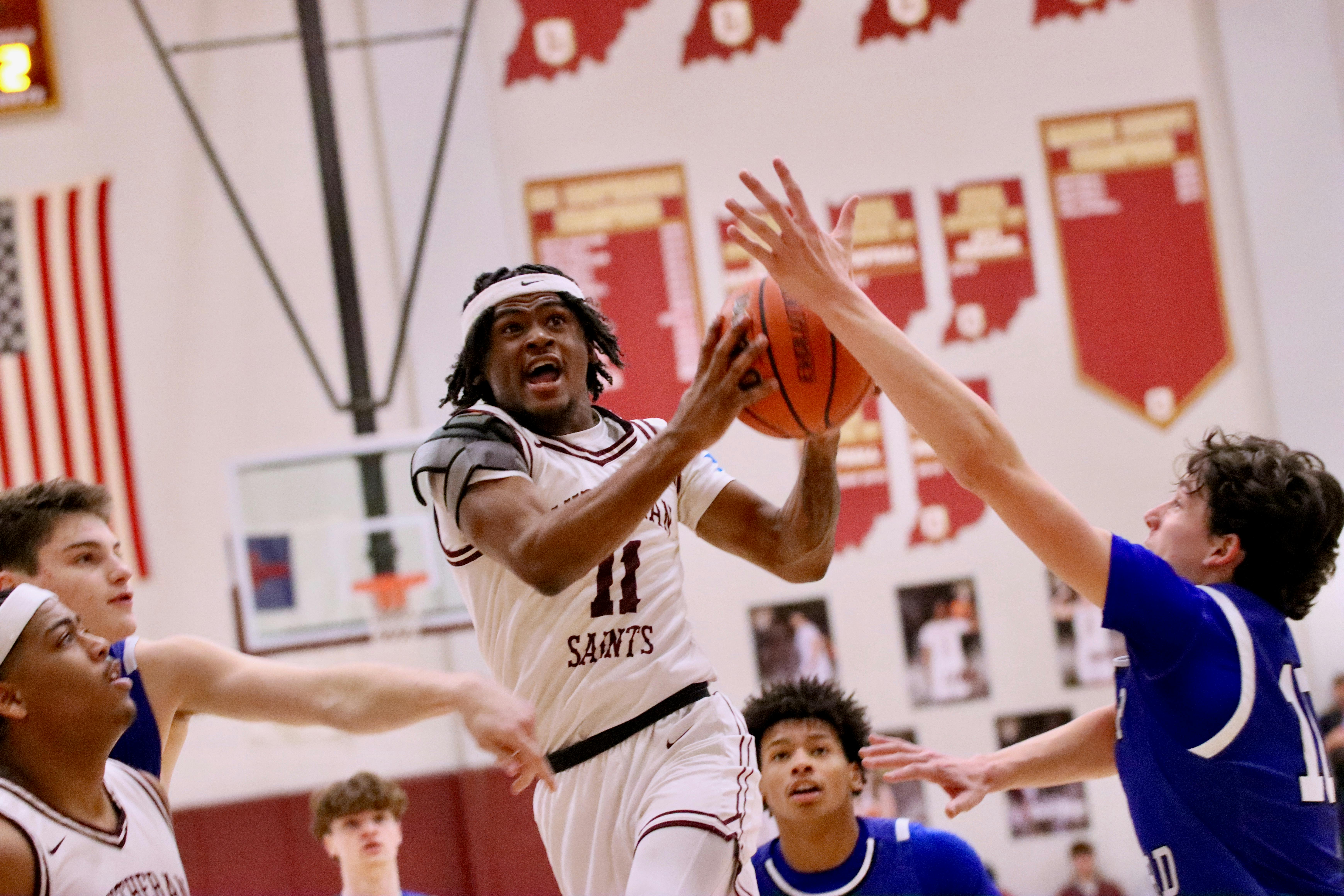 Person in white jersey with number 11 holding a basketball, defended by another person