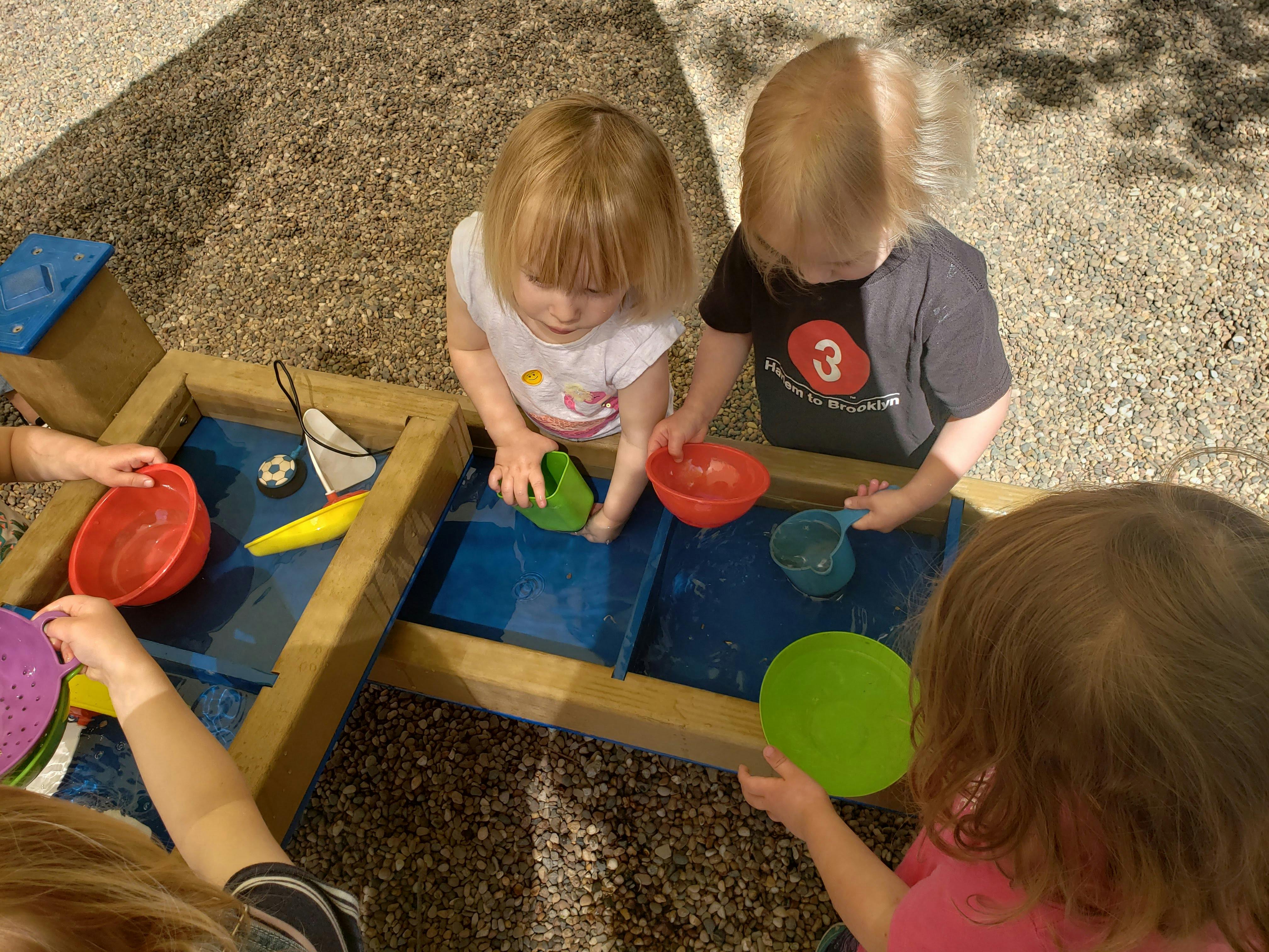 Children playing with water and colorful bowls at a water table