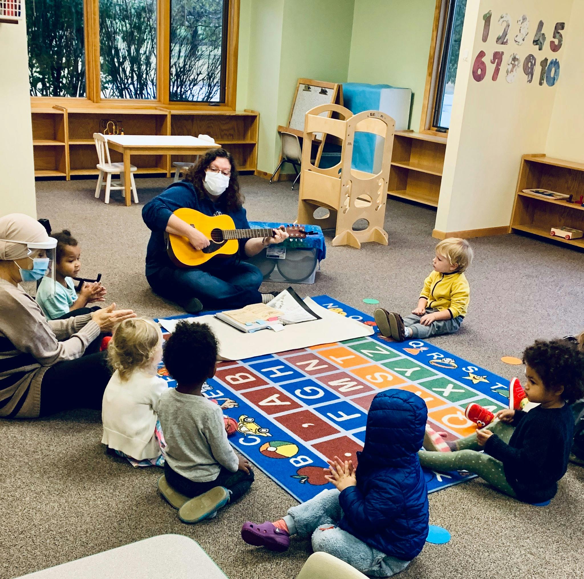 Person playing guitar for a group of children in a classroom