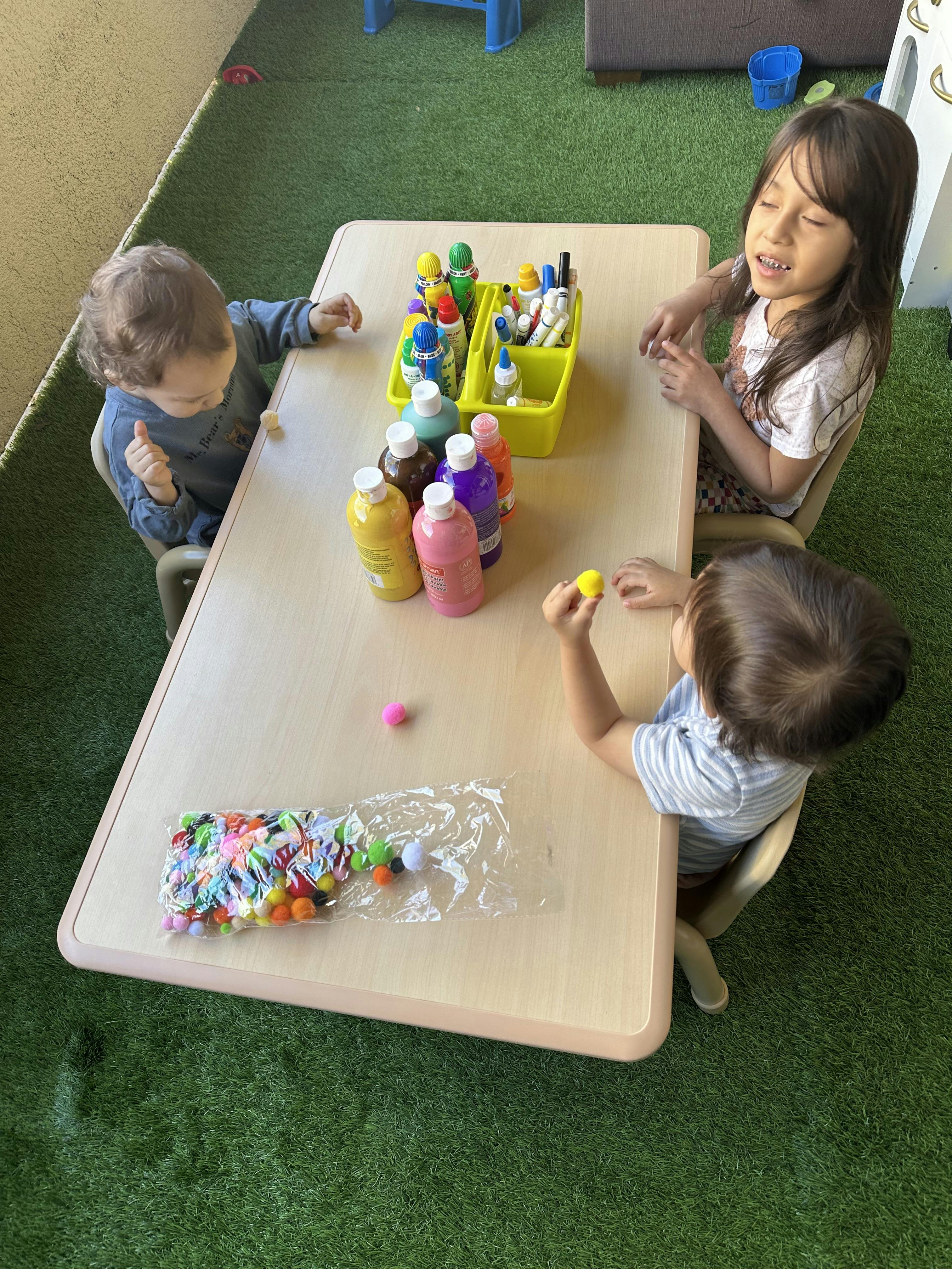 Three children sitting at a table with art supplies