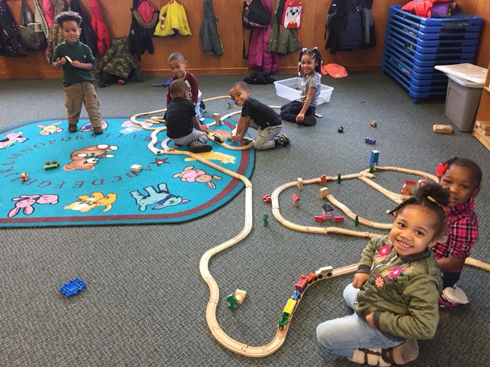 Children playing with toy trains on the floor