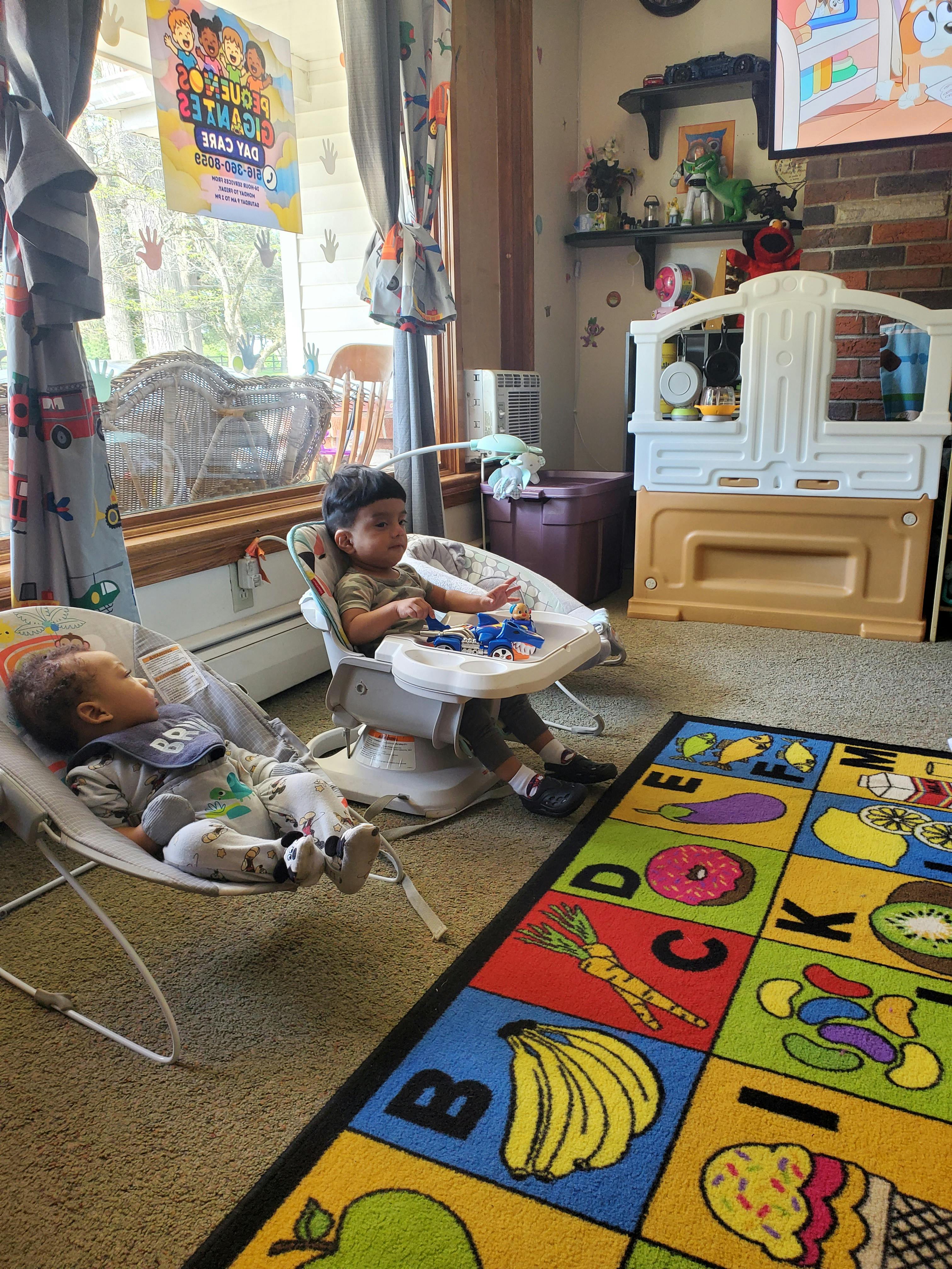 Two young children in high chairs on a colorful rug in a room