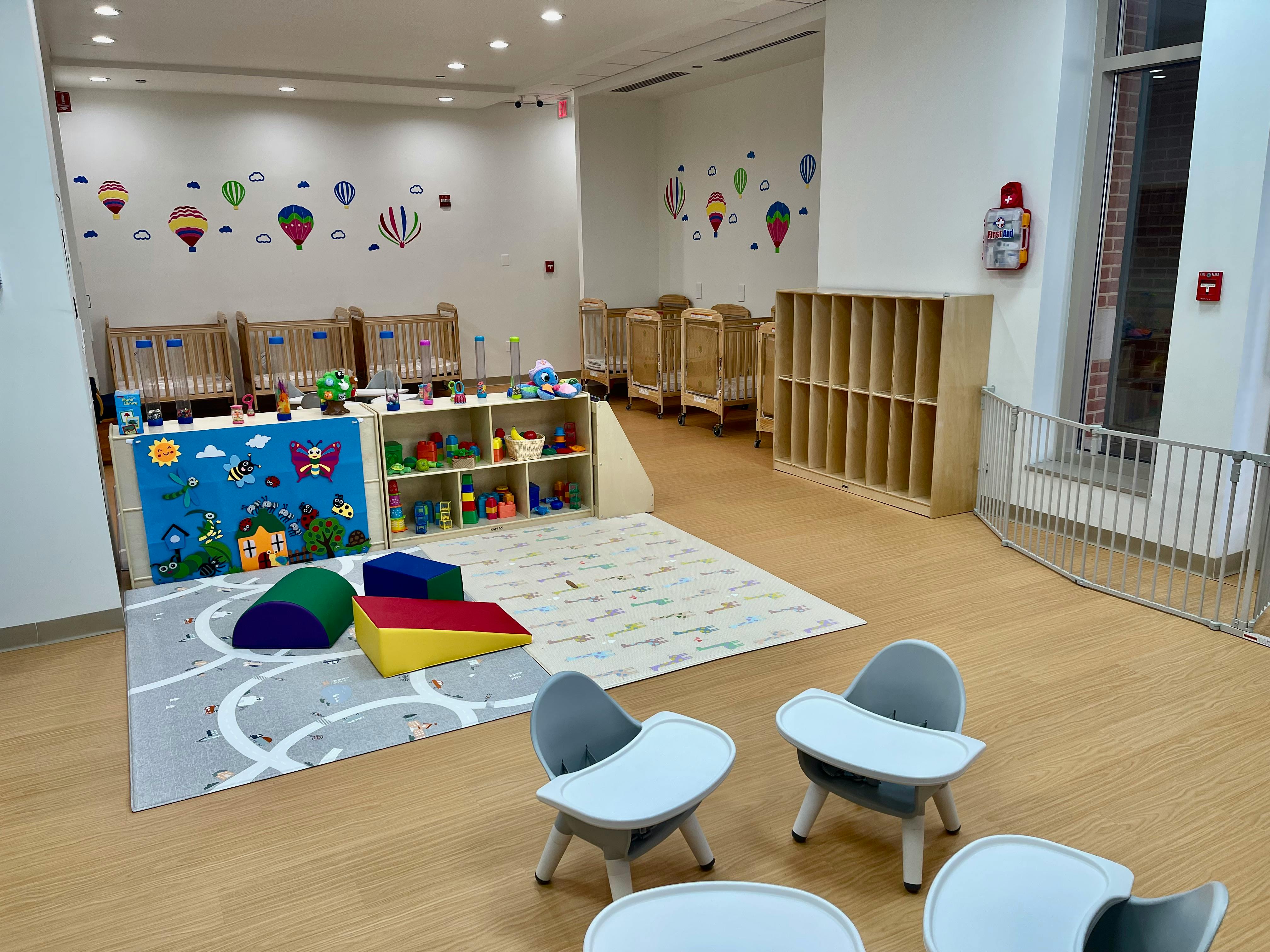 Daycare room with cribs, play mats, and small chairs