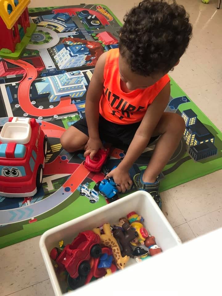 Child playing with toy cars on a playmat