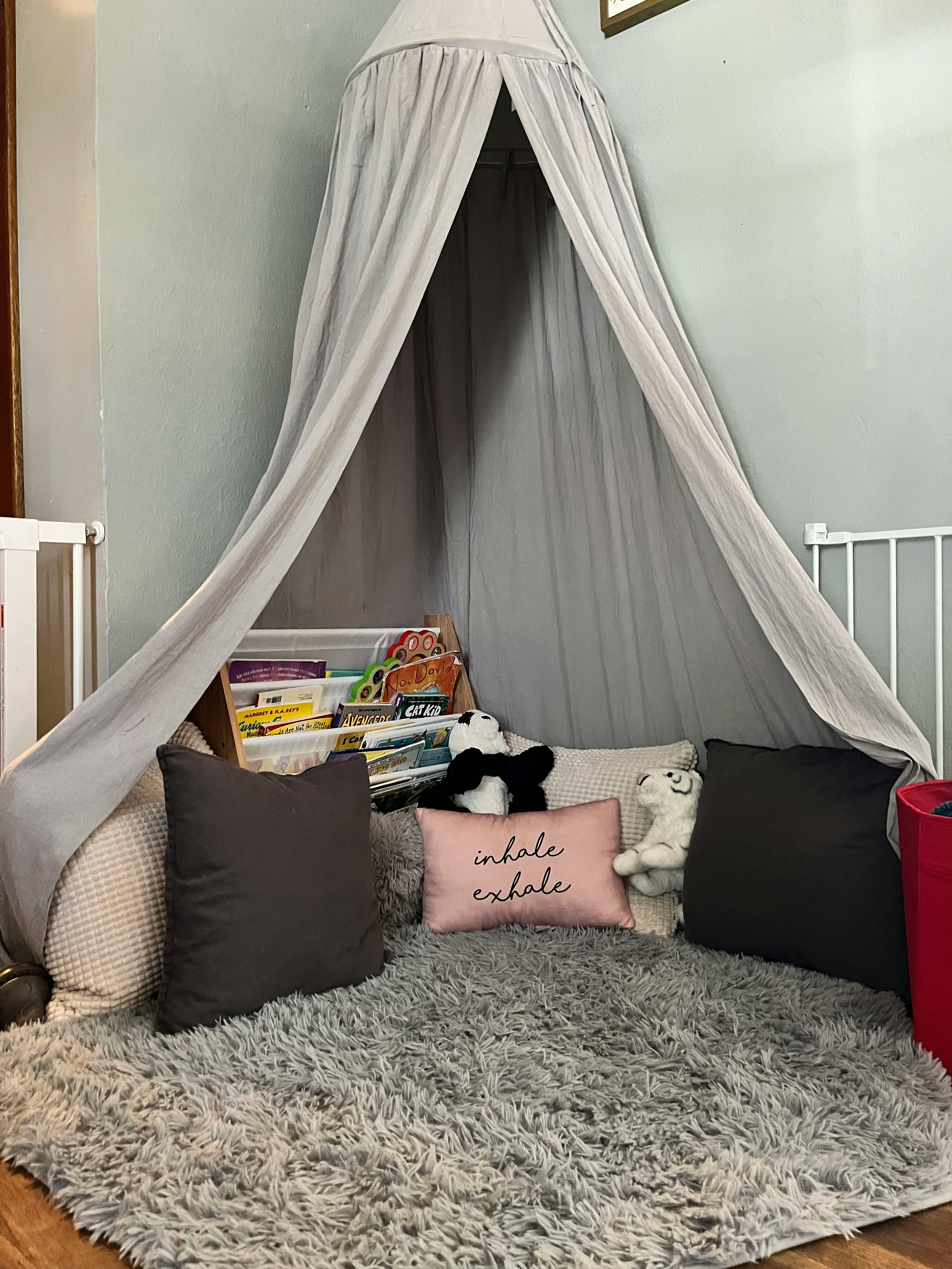 Reading nook with a canopy, pillows, stuffed animals, and books