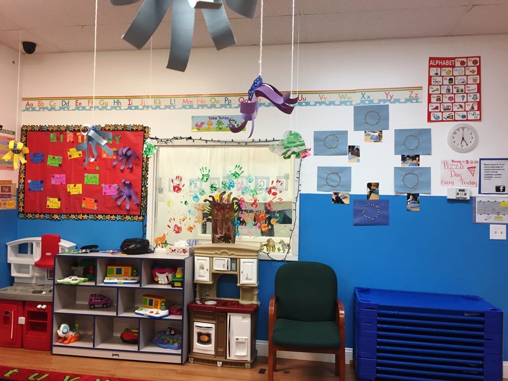 Classroom with children's artwork, play kitchen, and storage shelves