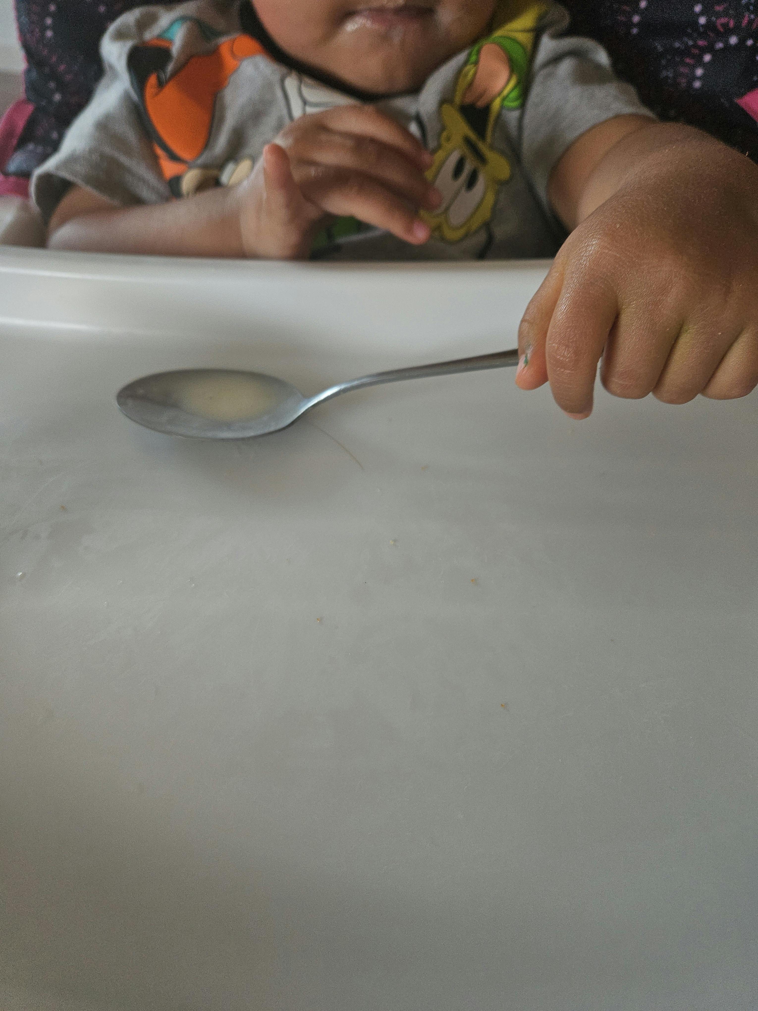 Child's hand holding a spoon with food