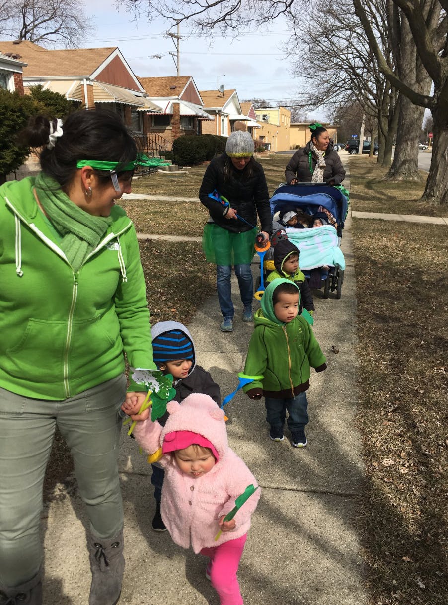 People walking with children on a sidewalk, some in a stroller, on a sidewalk