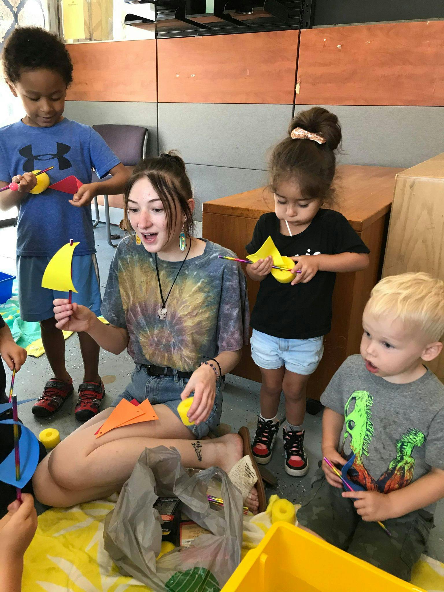 Person and three children making crafts