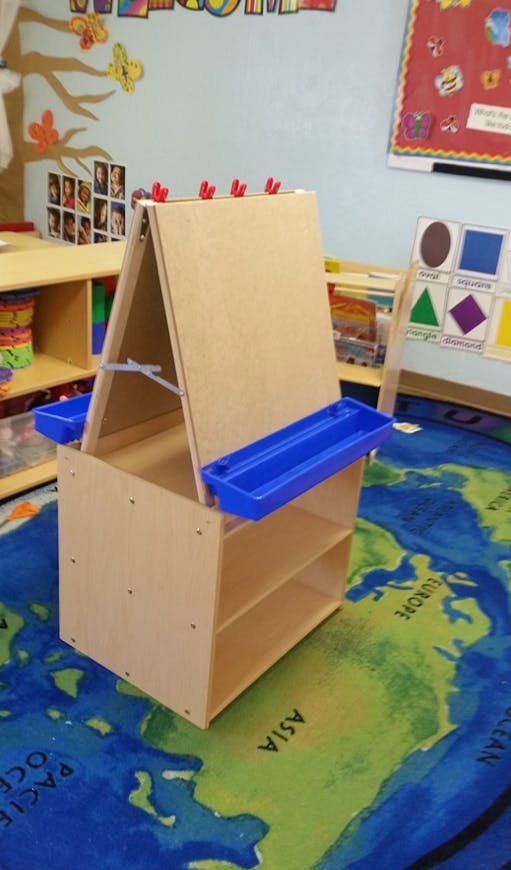 Wooden art easel with blue trays in a classroom