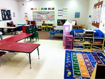 Classroom with tables, chairs, and an alphabet rug