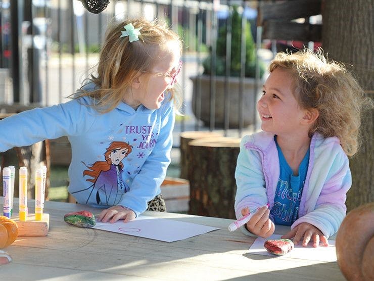 Two children interacting at a table with art supplies