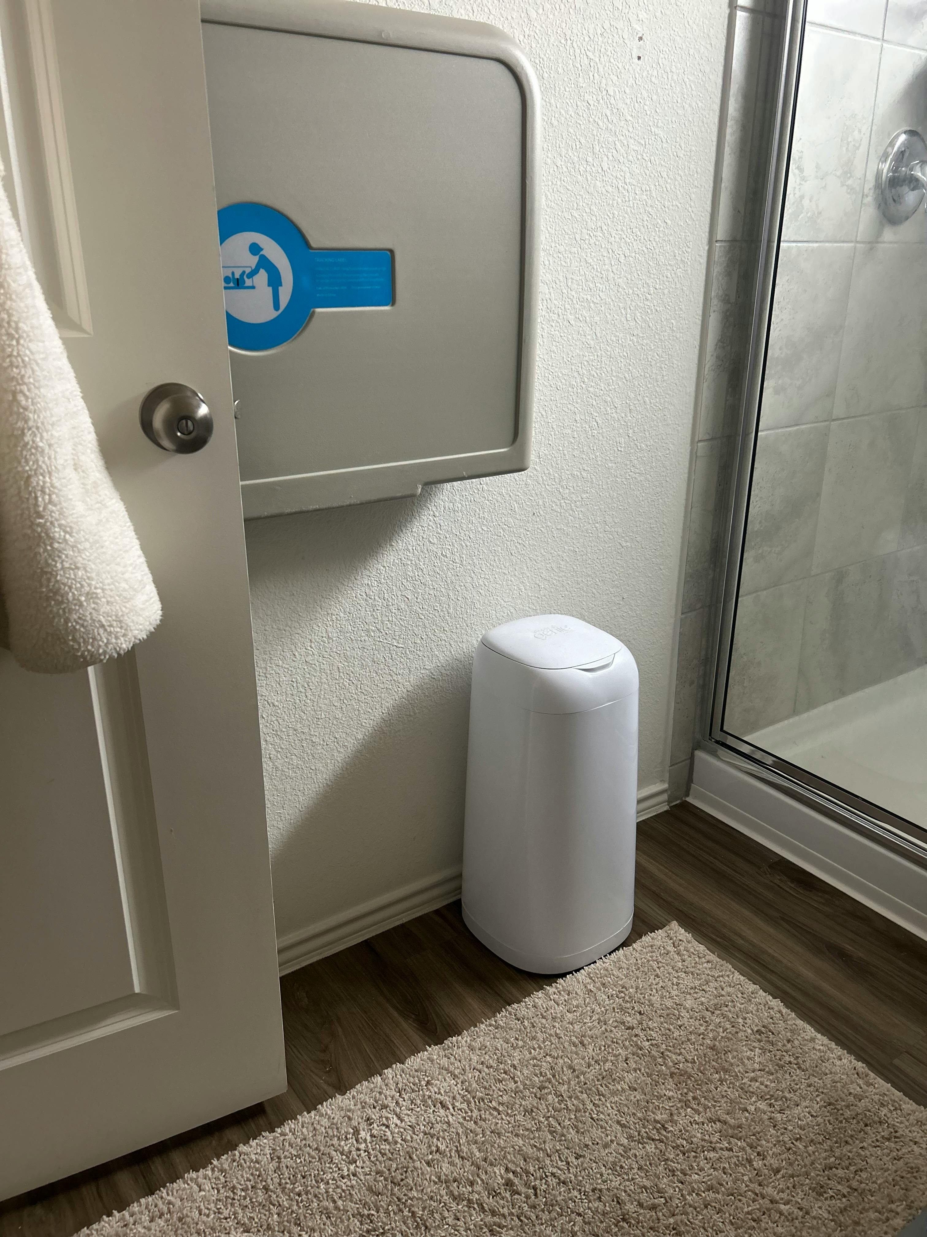 Baby changing station with a blue icon on a wall next to a white door