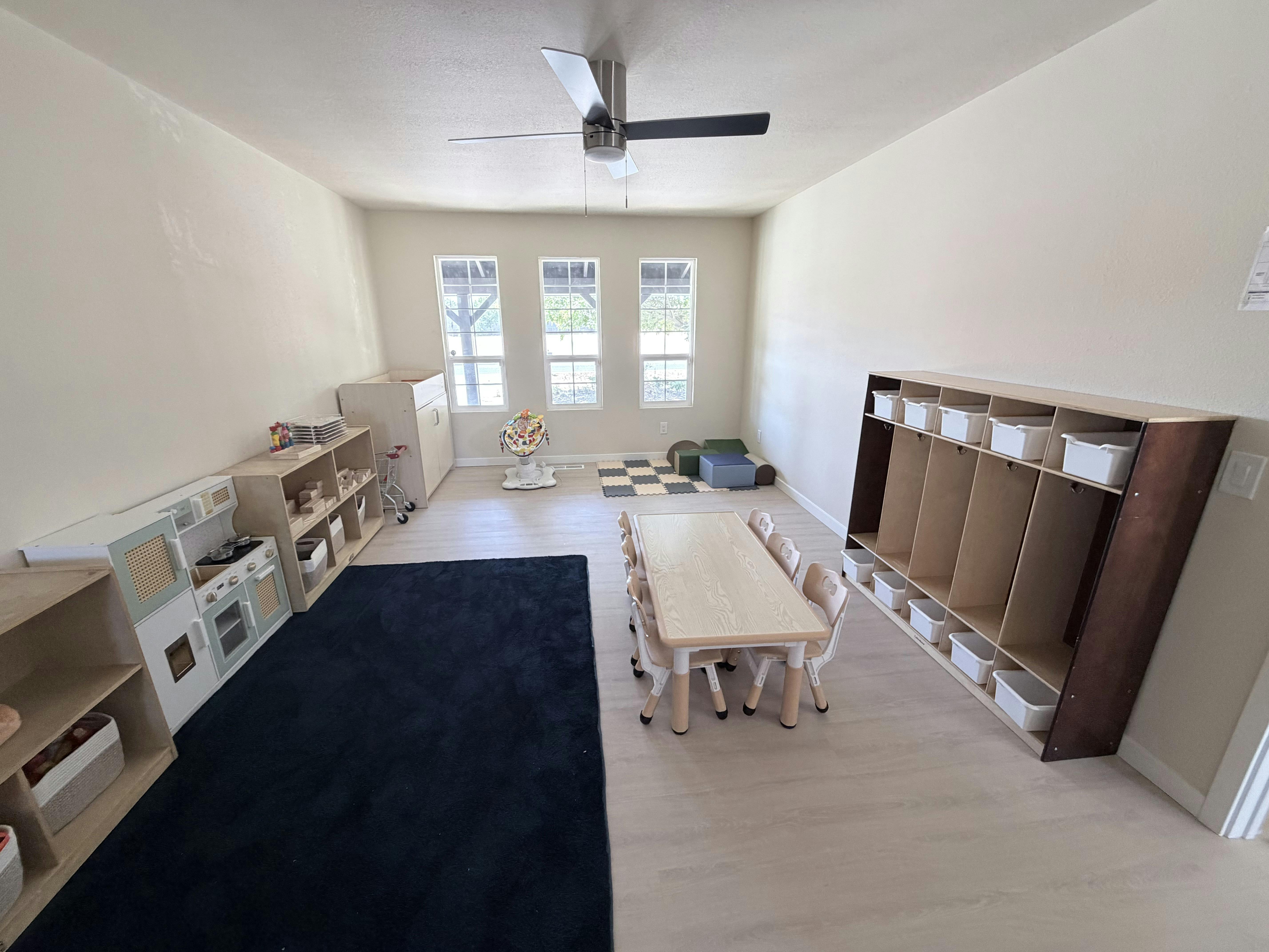 Childcare room with small table and chairs and wooden toy storage shelves