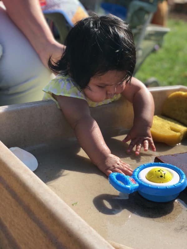 Child playing with a toy in a water table