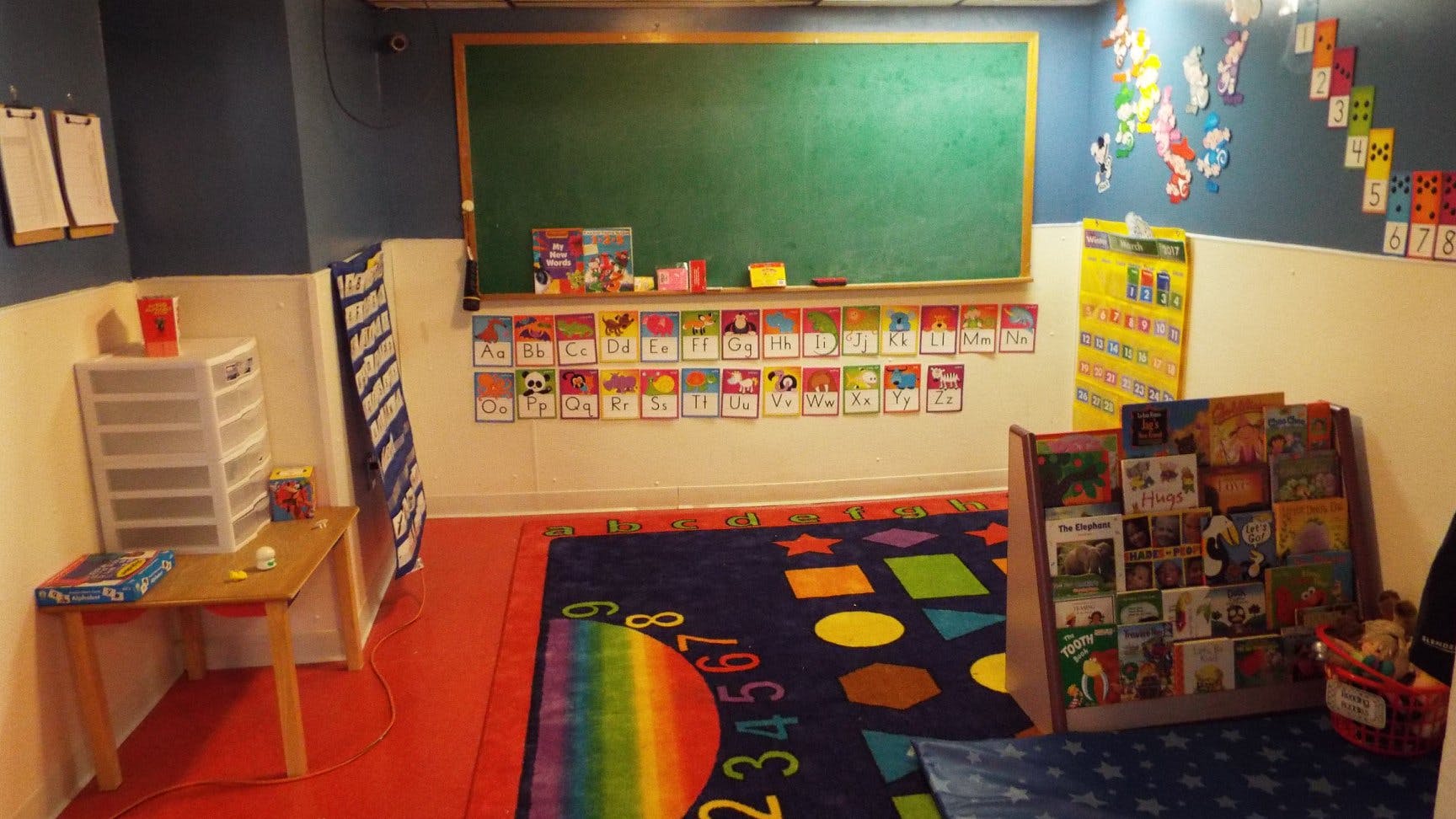 Classroom with a chalkboard, colorful rug, and book display