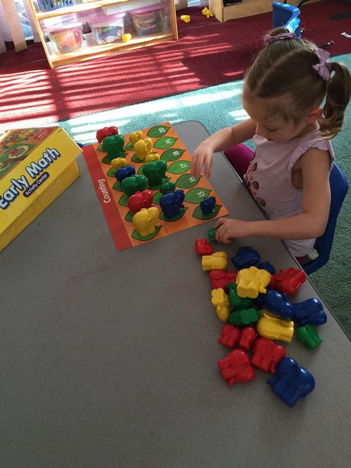 Child playing with colorful counting game pieces on a table