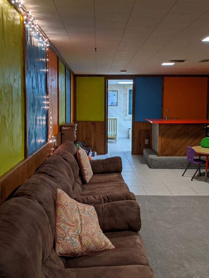 Brown sectional sofa with patterned pillows in a room with colorful walls
