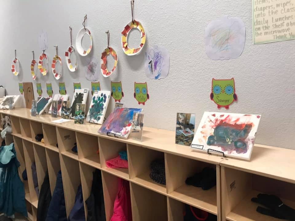 Children's artwork displayed on a wall above cubbies