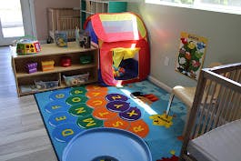 Playroom with alphabet rug, play tent, and wooden shelves