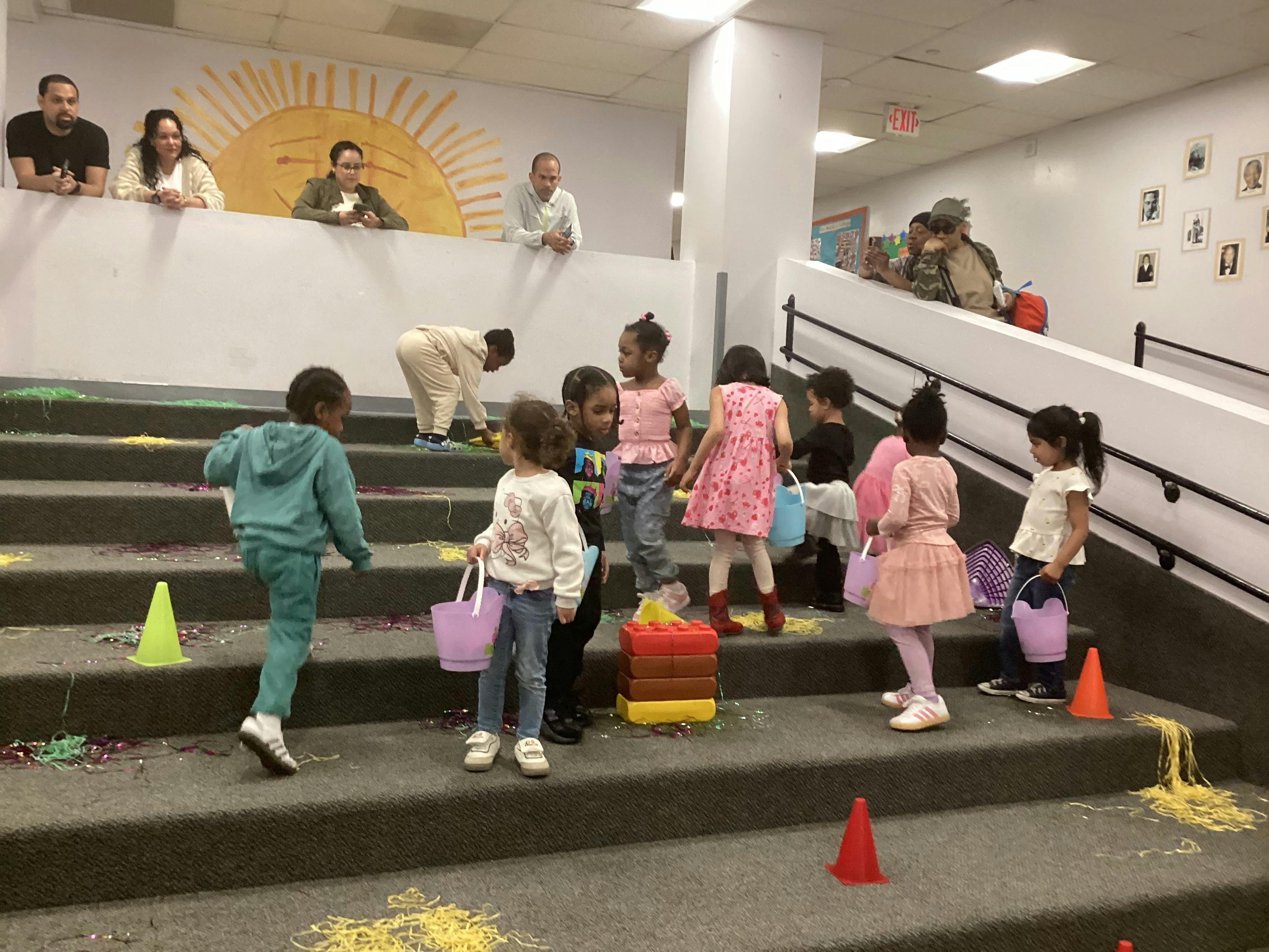 Children gathered on a staircase decorated with confetti and yellow and purple streamers