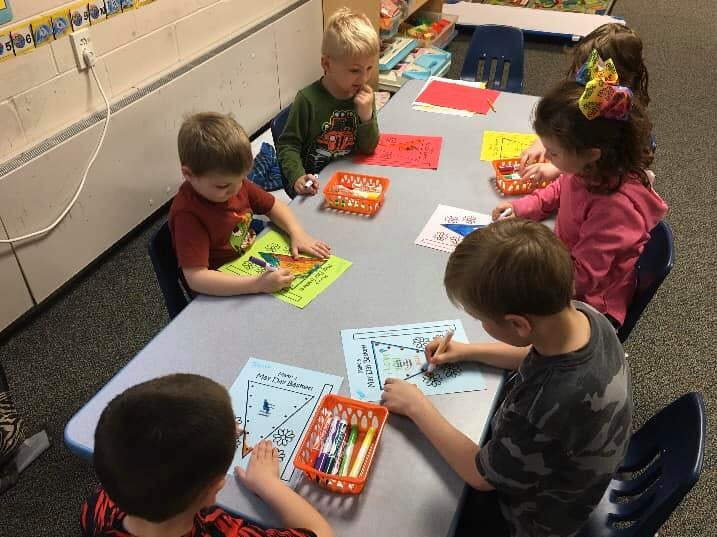 Children sitting at a table drawing and coloring