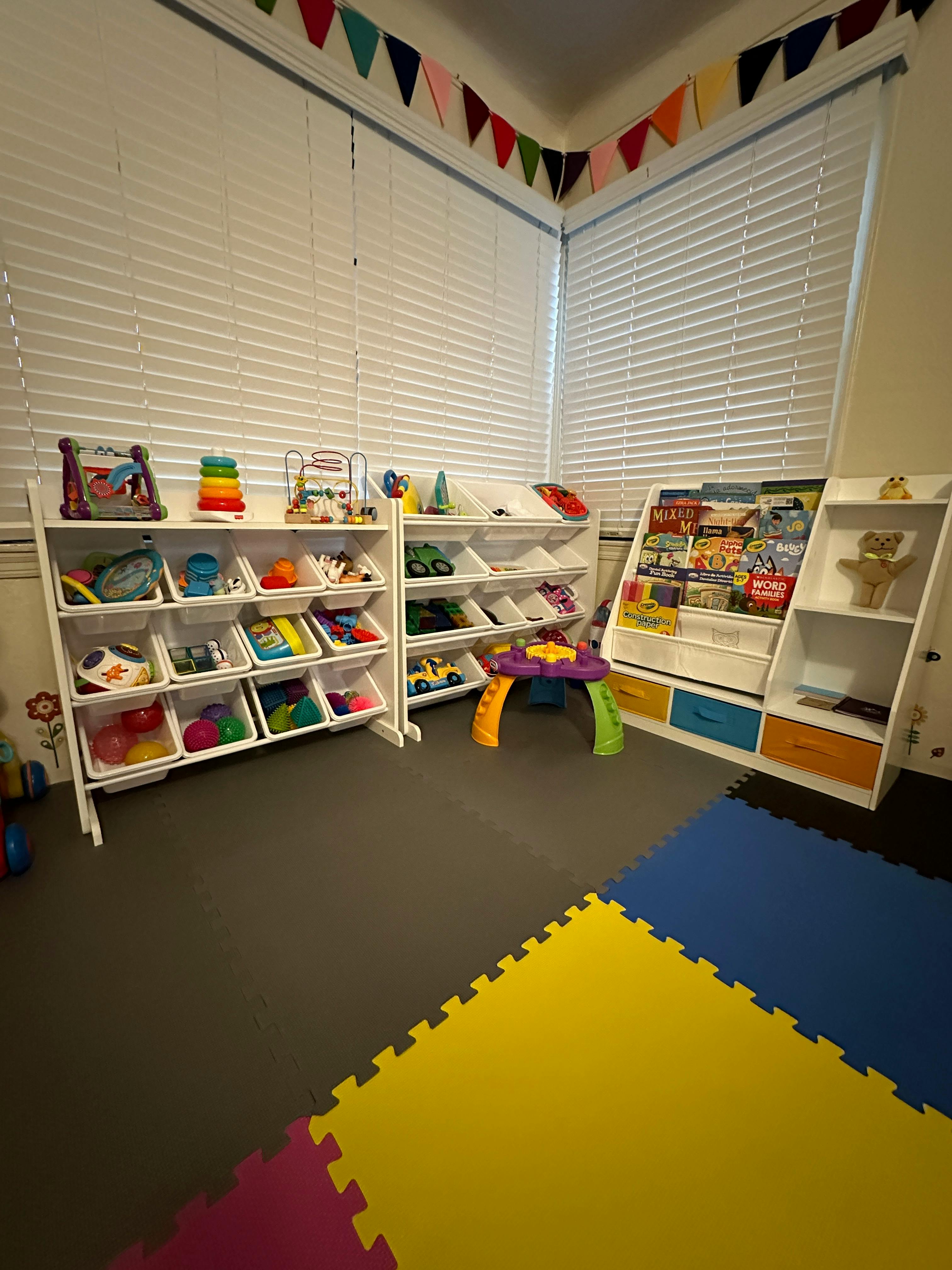 Playroom with toy shelves, books, and colorful floor mats