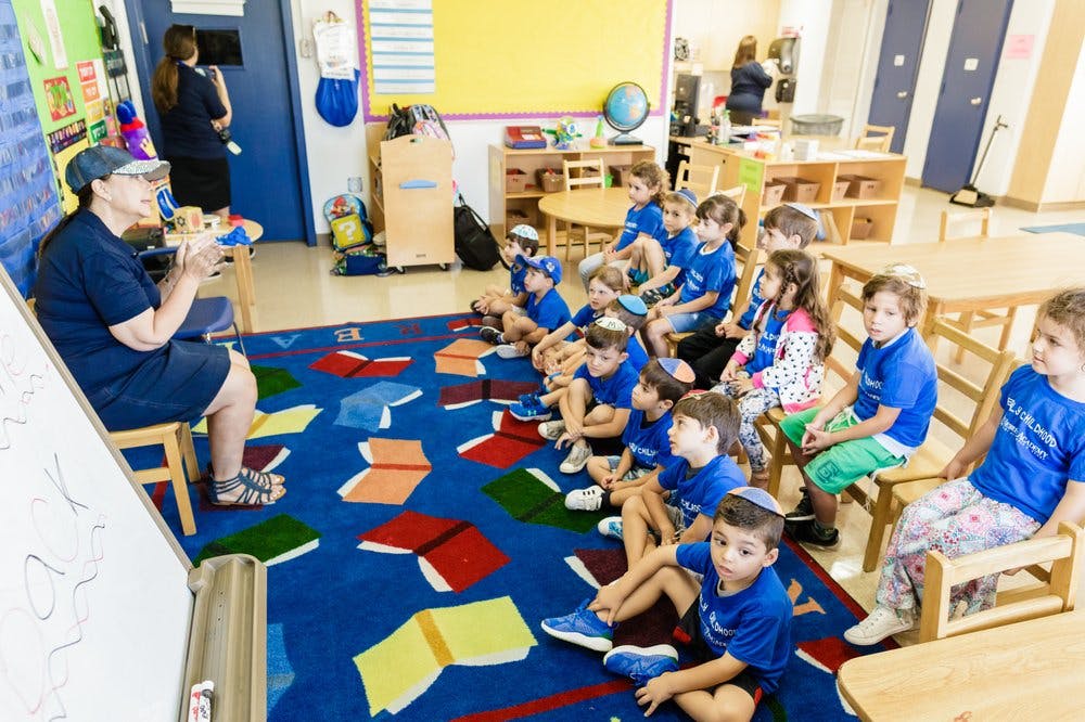 Adult speaking to a group of children in a classroom
