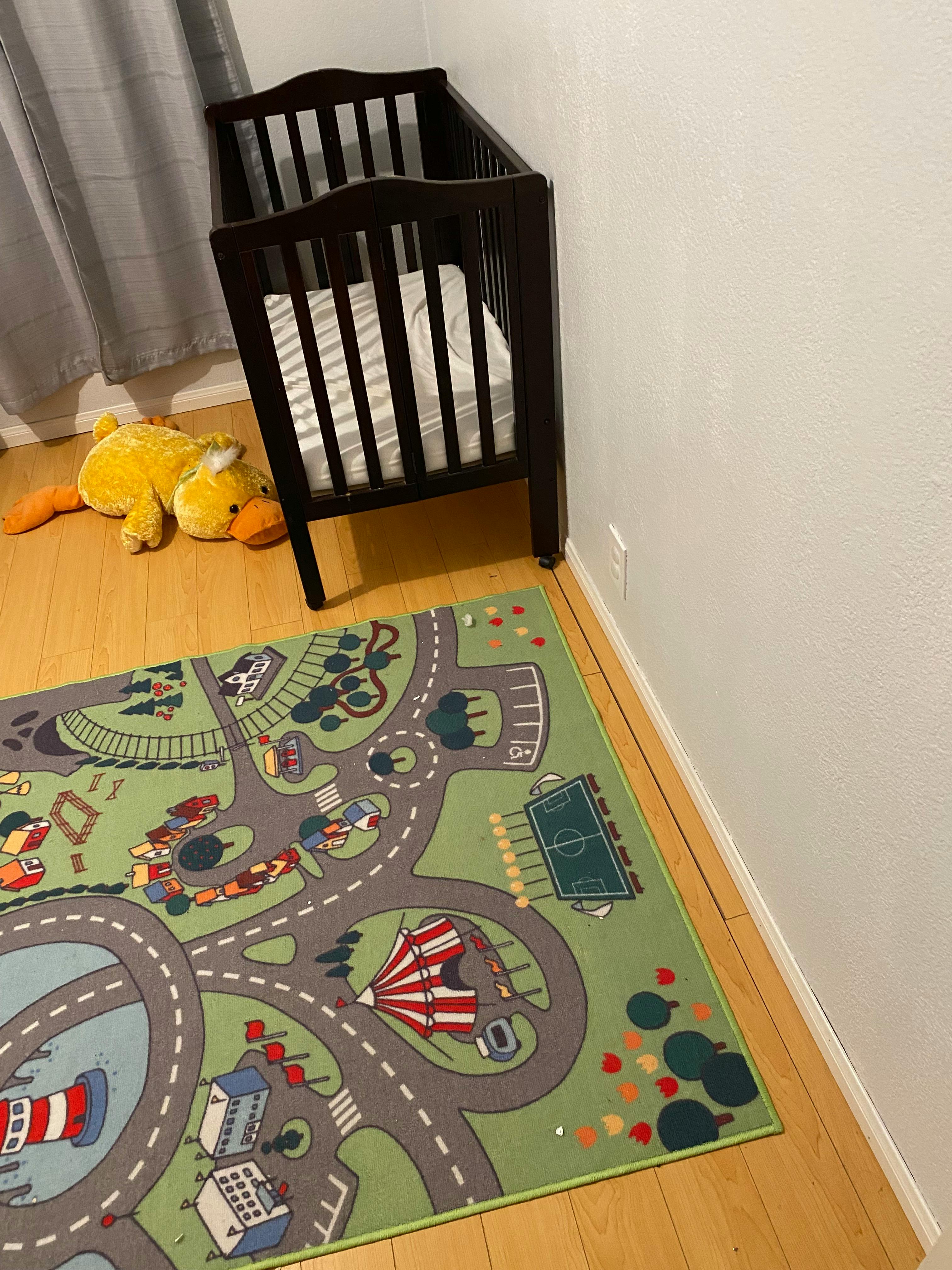 Baby crib next to a playmat with roads and buildings