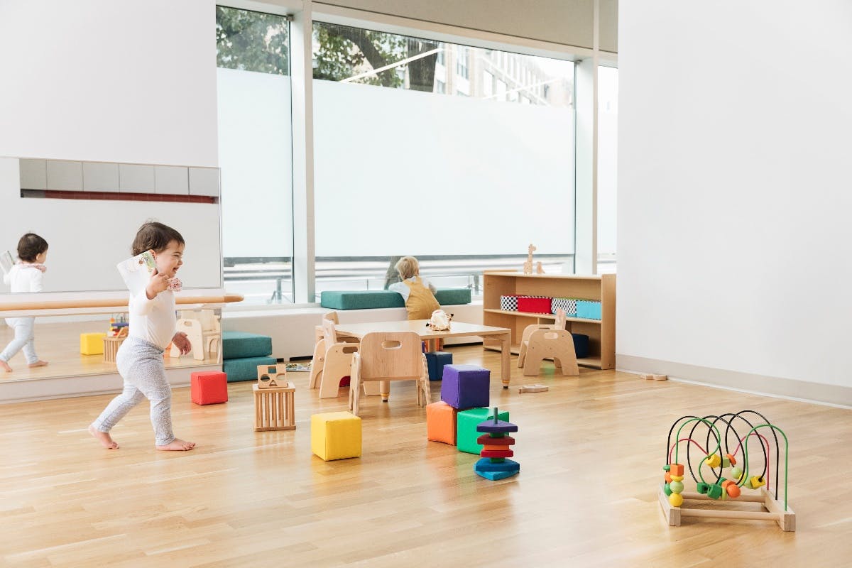 Child walking in a classroom with toys and furniture