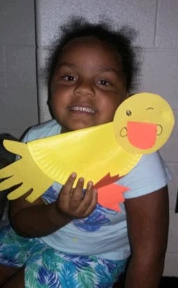 Child holding a yellow paper plate craft