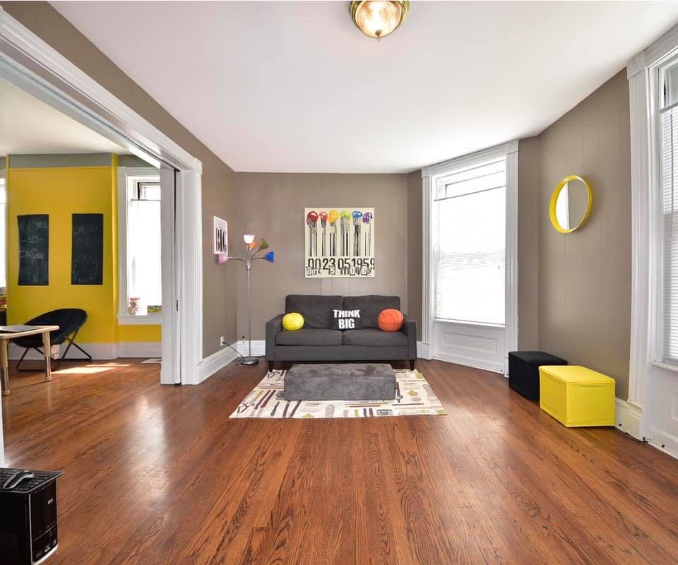 Living room with a gray sofa, rug, and yellow and black ottomans