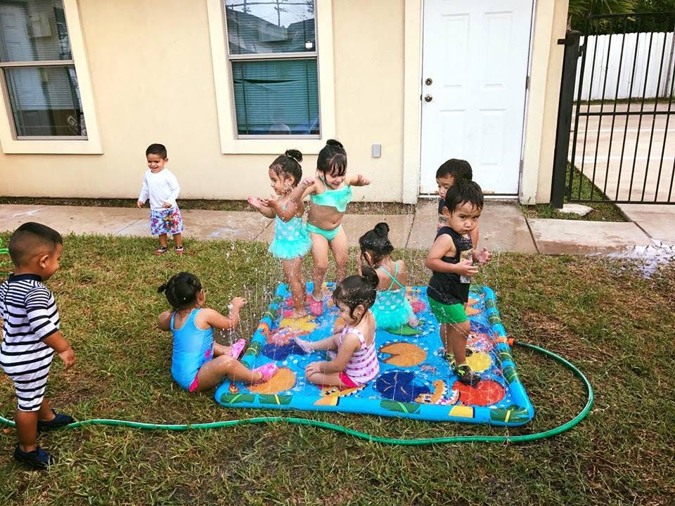 Children playing on a splash pad in a yard